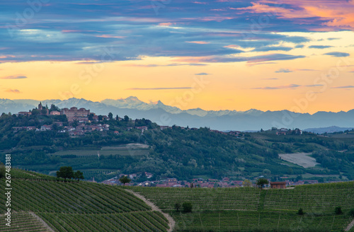 The village and castle of Magliano Alfieri, sunset light with alps mountain background. Langhe vineyards in Piedmont, Italy