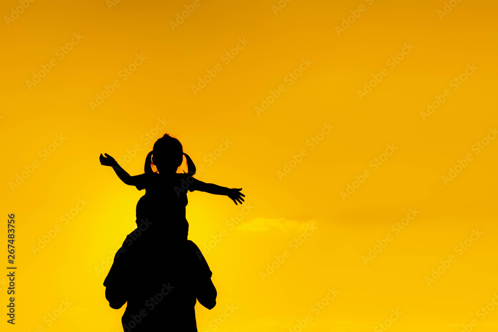 The family silhouette of the mother and child standing watch the sunset and the sky in orange in evening The family silhouette of the mother and child standing watch the sunset and the sky in orange in evening