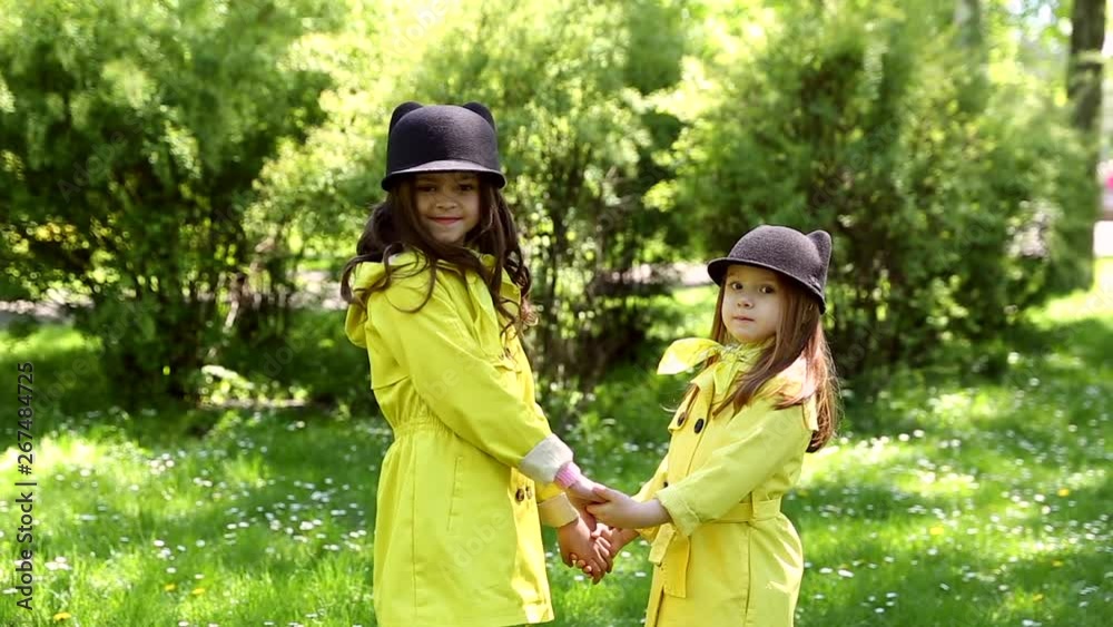 two young sisters playing together in the park on a sunny day two young sisters playing together in the park on a sunny day