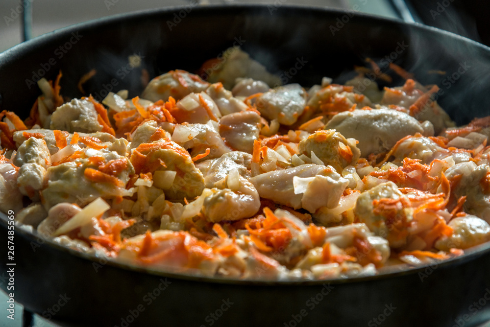 Cooking, sliced carrots and meat fried in a pan
