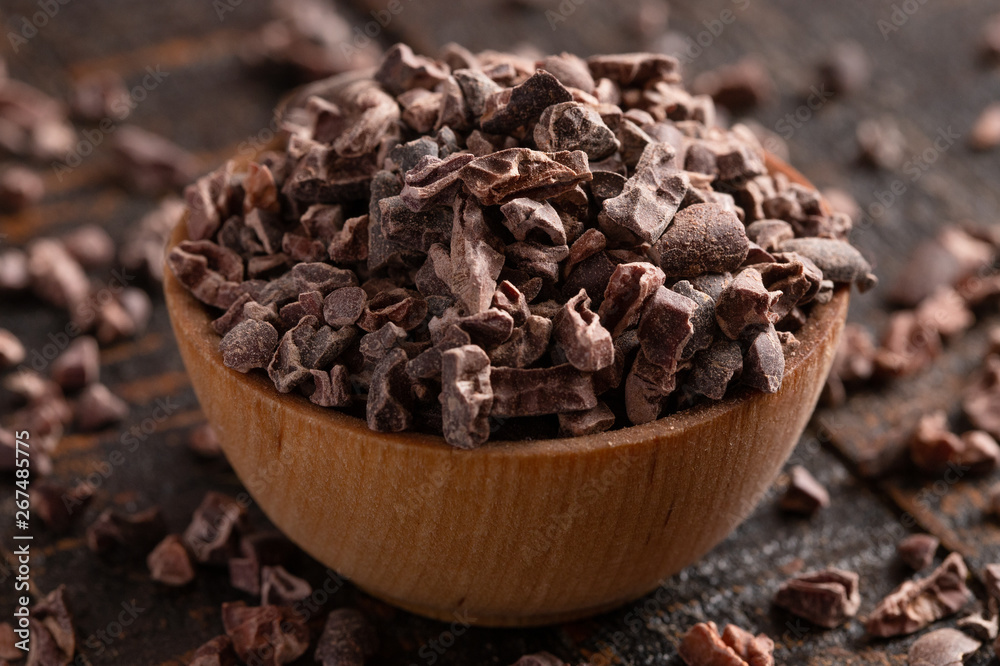 Bowl of Raw Chocolate Nibs on a Rustic Wooden Table