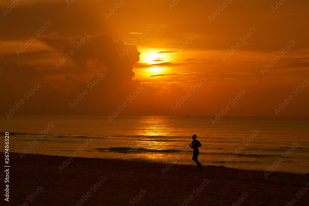 Silhouette of an athlete in the rays of sunset on the beach of a tropical island