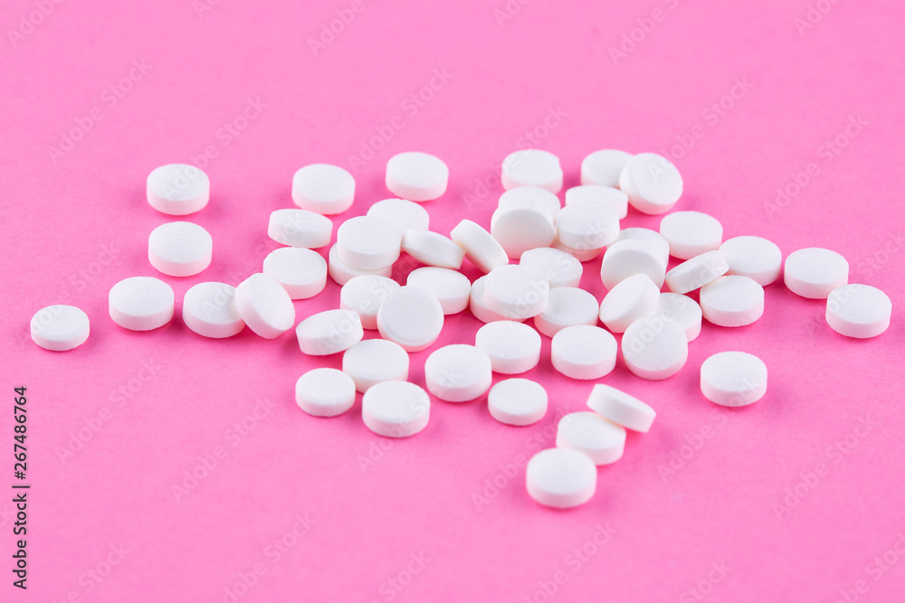 Heap of white pills on pink background