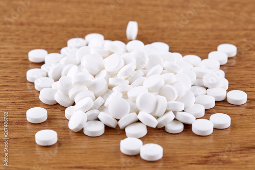Heap of white pills on wooden background
