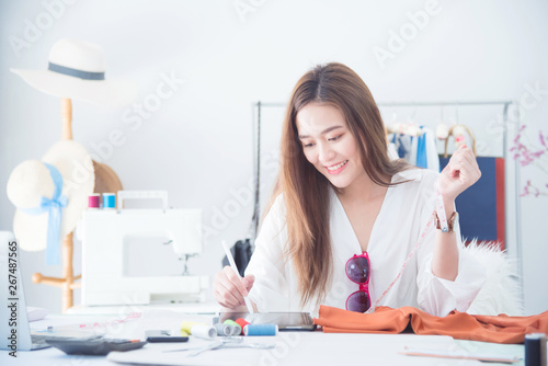 Portrait beautiful asian designer woman work with tablet computer in tailer fabric fashion small business shop. SME business concept photo