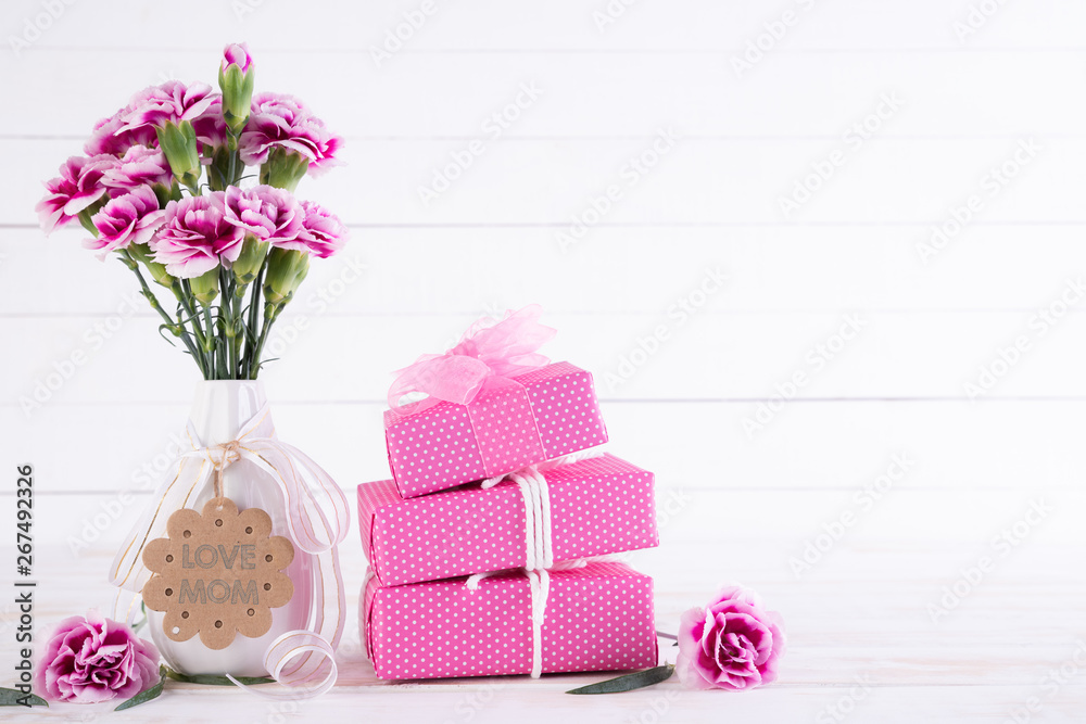 Happy mothers day concept. Gift box with pink carnation flower on white wooden table background. Happy mothers day concept. Gift box with pink carnation flower on white wooden table background.