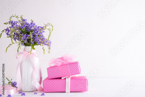 Happy mothers day concept. Gift box with purple flower on white wooden table background.