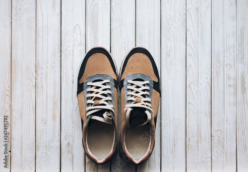 A pair of suede sneakers on a rustic wooden background. The concept of jog and sports shoes. Top view, copy space.