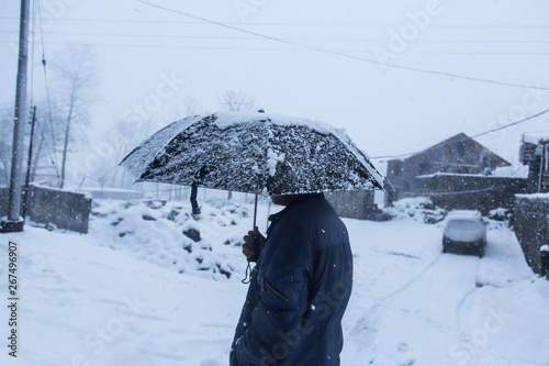 Winter snow falling,a person walking with black umbrella, background - image