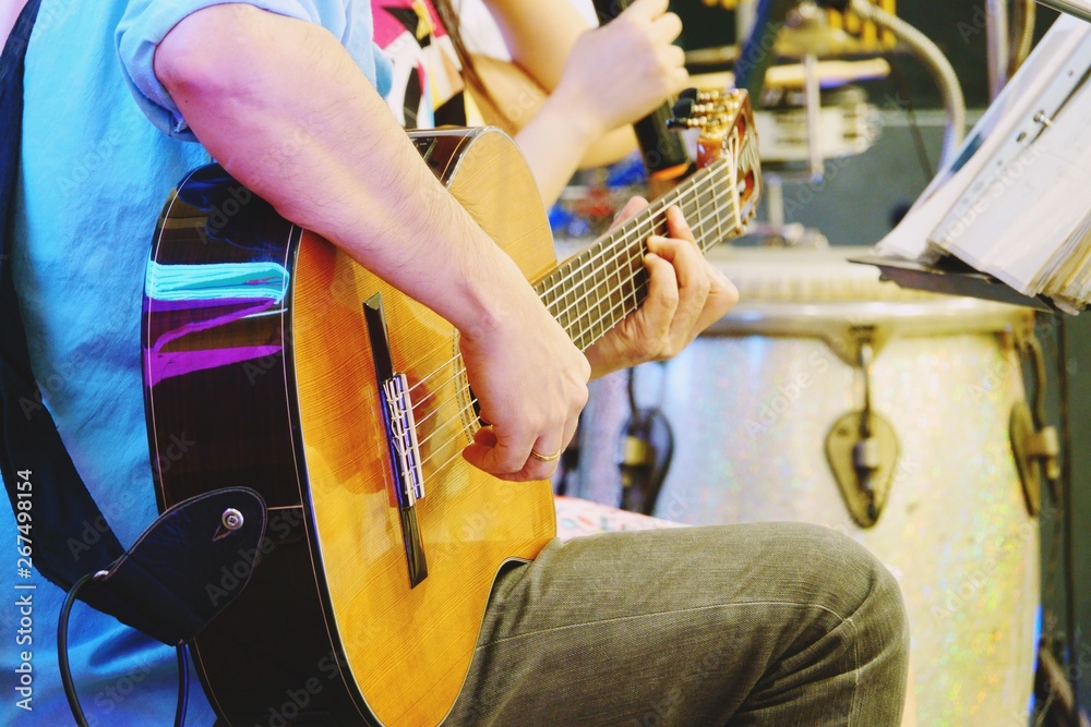 Close up of hands of a man playing a classic guitar on stage