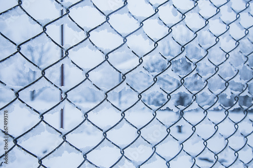 Wire fence in the snow. Fence background. Metallic net with snow. Metal net in winter covered with snow. Wire fence closeup. Steel wire mesh fence vintage effect. - Image