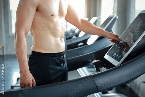image of healthy and sexy caucasian muscle man in shirtless who setting up running machine in gym © feeling lucky