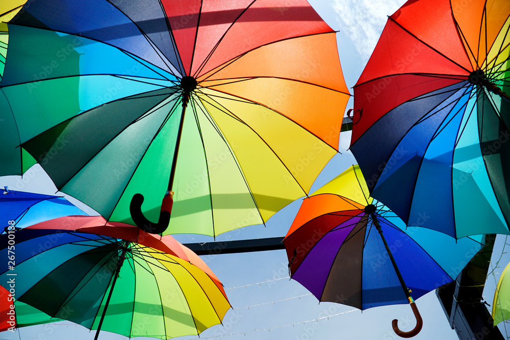 Colorful umbrellas background. Colorful umbrellas urban street decoration.  Hanging Multicolored umbrellas over blue sky. umbrellas with many colors