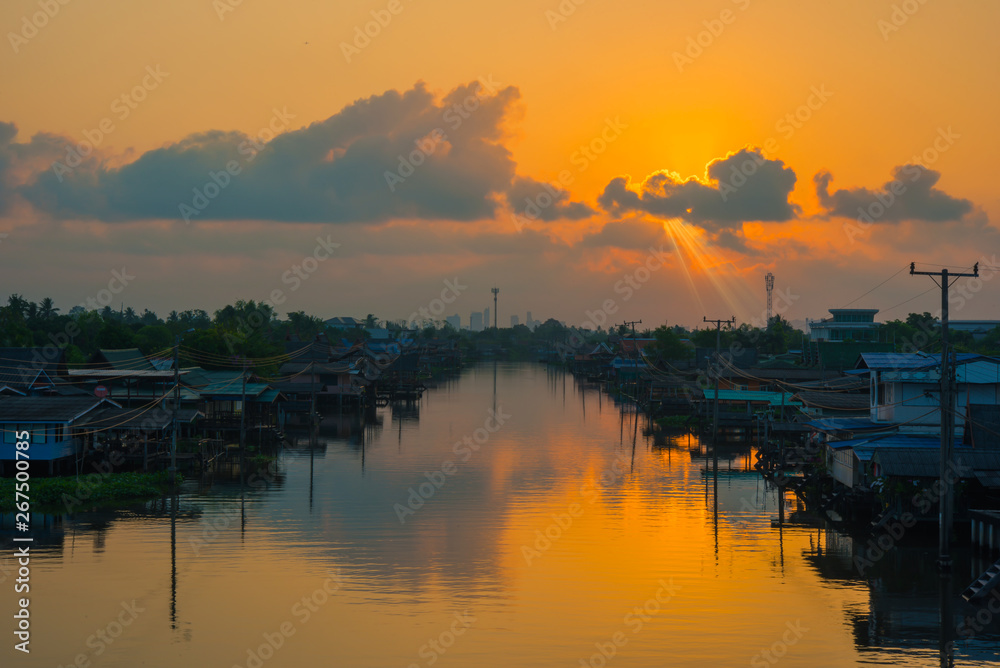 Riverside village with sunset sky and dark clouds, Reflection on the water surface, Bangkok,Thailand-Image