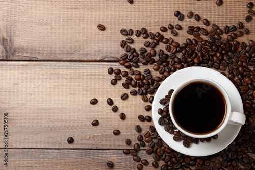 Cup of coffee and beans on wooden background.