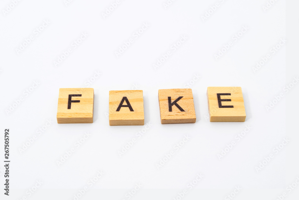 FAKE word written in wooden blocks isolated on white background. FAKE word written in wooden blocks isolated on white background.