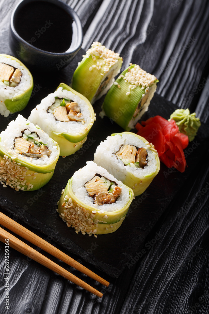 Japanese rolls green dragon with avocado, omelette tamago, sesame and cucumber closeup on a plate. vertical Japanese rolls green dragon with avocado, omelette tamago, sesame and cucumber closeup on a plate. vertical