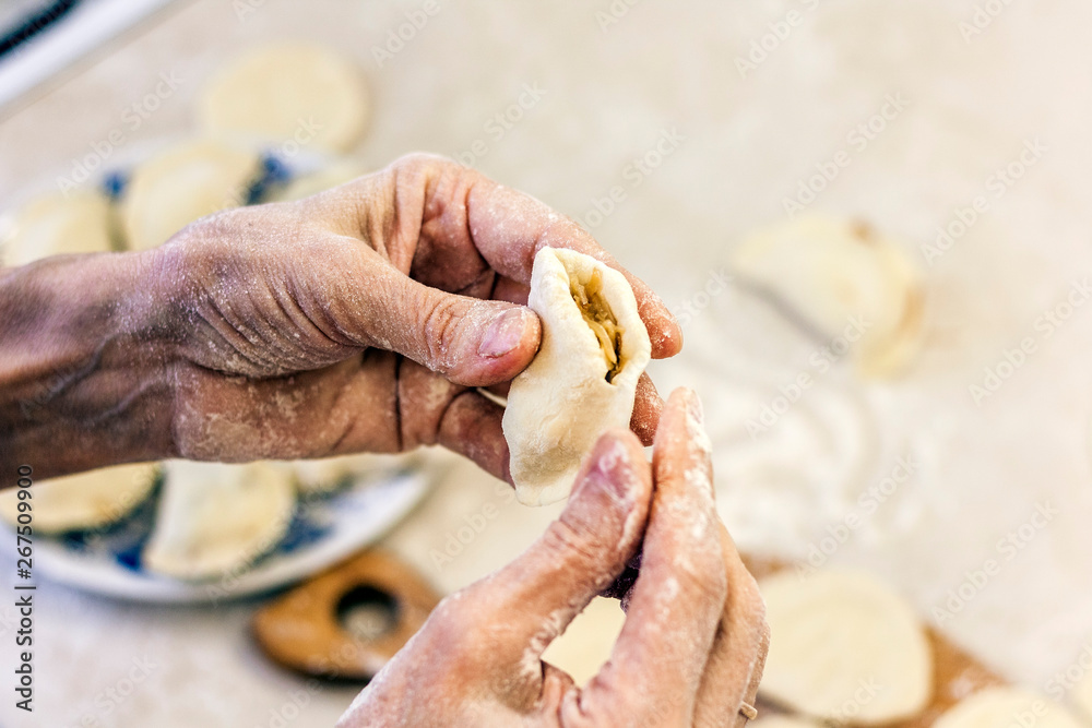 Dumplings. Dough with cabbage filling on the cook's hands.