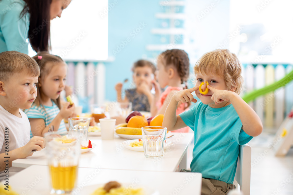 Group of kids have lunch in daycare. Child boy dabbles at the table Group of kids have lunch in daycare. Child boy dabbles at the table