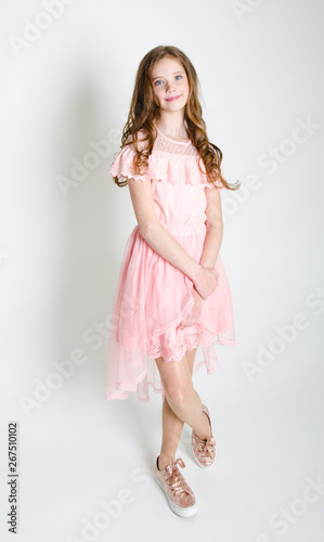 Portrait of adorable smiling little girl child in princess dress with curl hair standing isolated