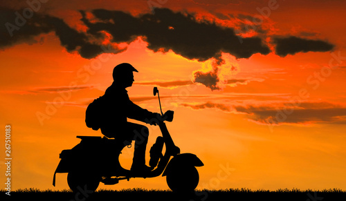 Silhouette biker with his motorbike on blurry blue sky background