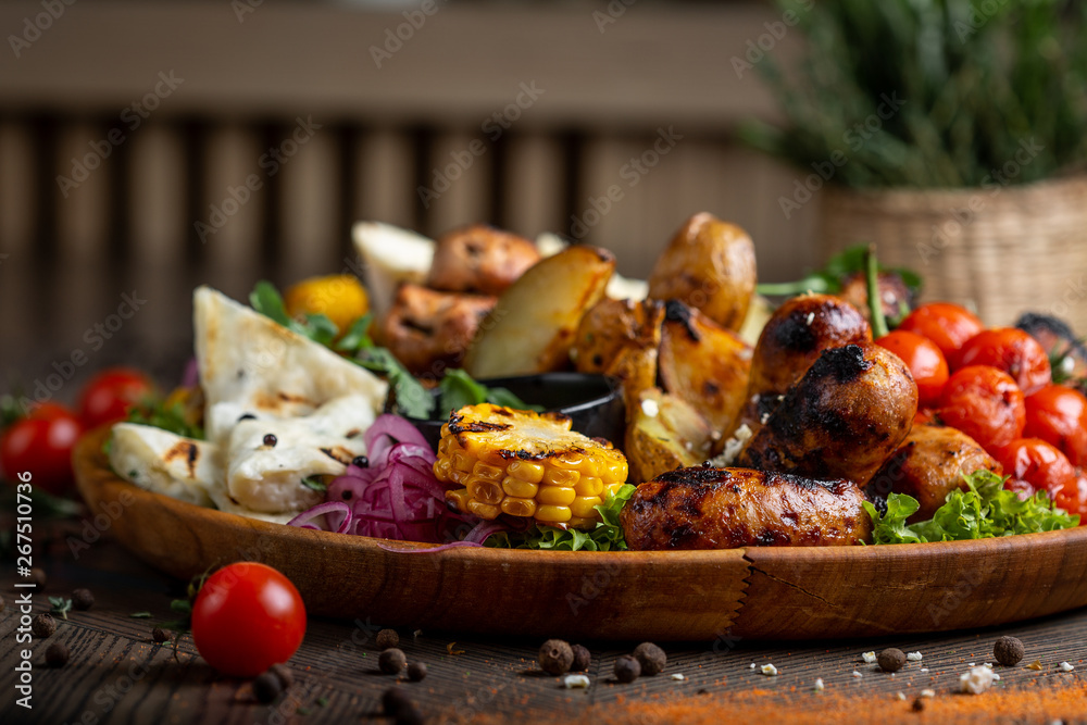 Tasty dish with meat and vegetables, baked pork, cowboy grill, grilled potatoes with sauce. Assorted tasty grilled meat with vegetables and herbs