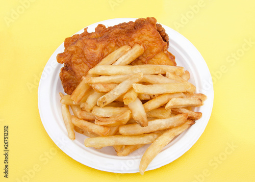 White paper plate with fish and chips on yellow table cloth. Popular street fair food.