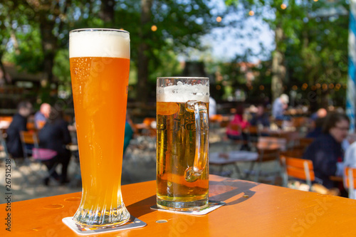 A wheat beer and a pils are standing on a table in a beer garden photo