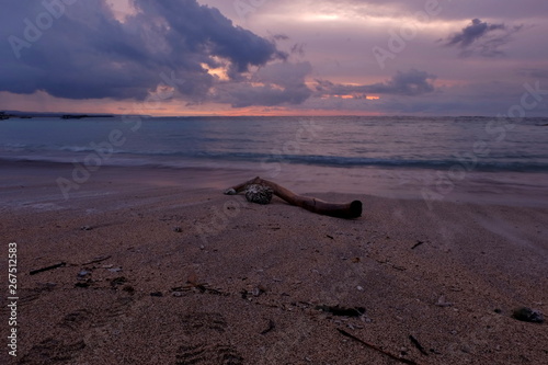 A piece of wood on the sand of Kuta Bali beach which was photographed at dusk, with beautiful sky colors © onyengradar