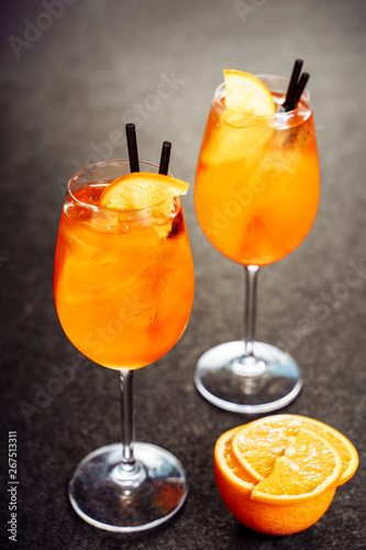 Aperol Spritz Glass Cocktail Drink with Orange Ice. Bar Wine Aperitif with Gin and Prosecco on Black Background. Night Mixed Sparkling Beverage for Tropical Nightclub. Spritzer Vertical Commercial
