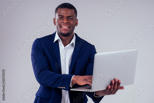Happy successful young african american businessman portrait wearing a crown holding a laptop lottery winner