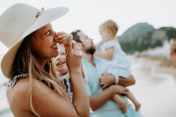 A young family with two toddler children having fun on beach on summer holiday.
