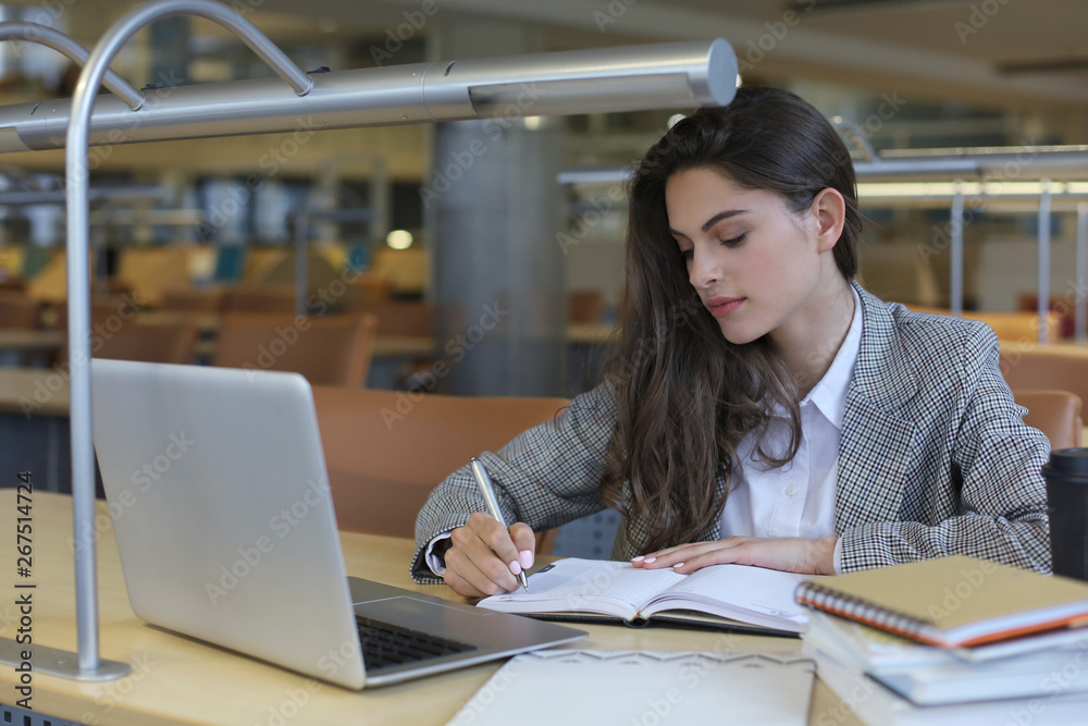 Portrait of a pretty female student with laptop in library. Portrait of a pretty female student with laptop in library.