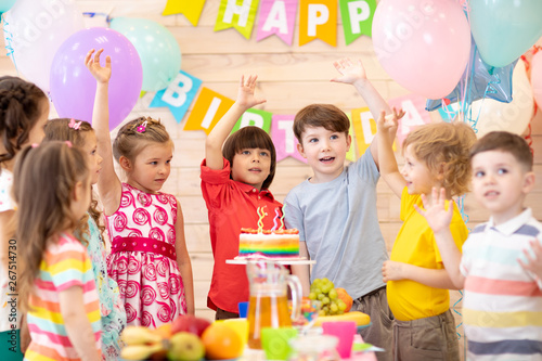 Group of little children celebrating birthday merrily, Excited friends. Cheerful excited kids visiting great birthday party and smiling while putting their hands up
