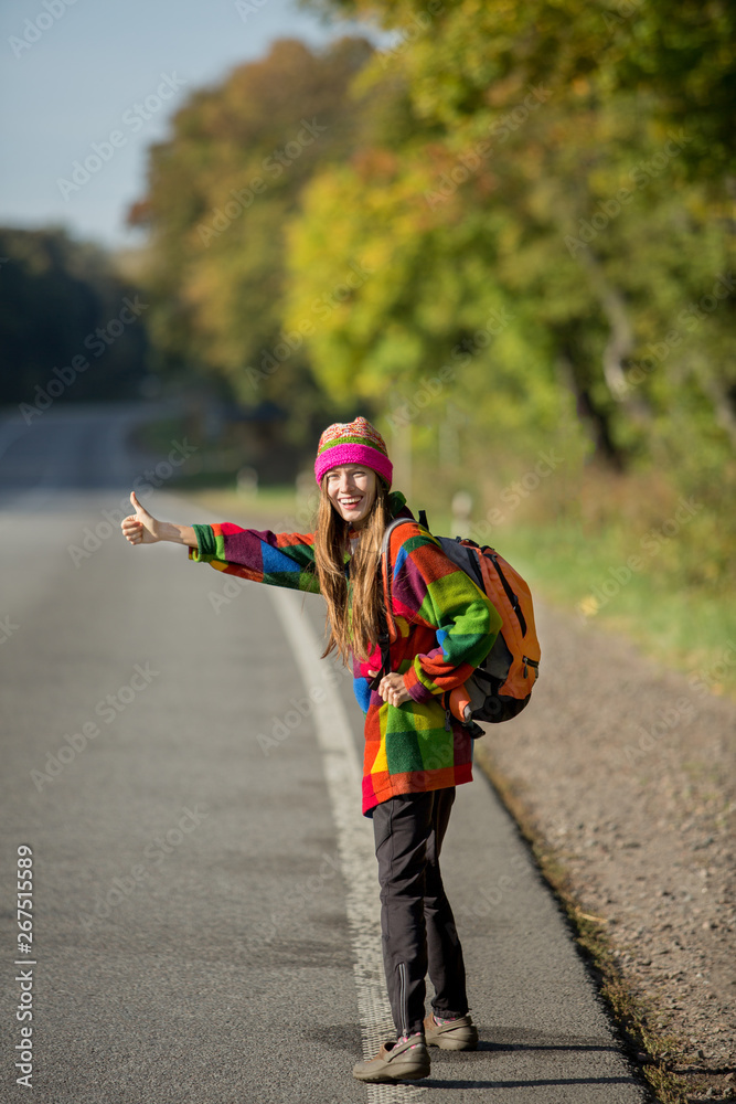 Spring or autumn travel woman hitchhiking on a road
