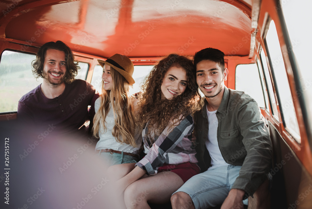 A group of young friends on a roadtrip through countryside, sitting in a minivan.