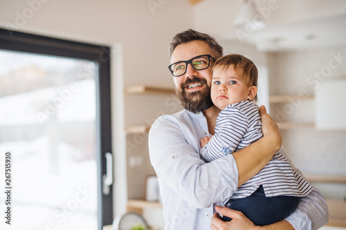 A portrait of father with a toddler girl indoors, hugging.