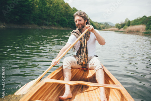 Canoeist enjoy canoe ride on a sunny day. Beaded man paddling a canoe on water