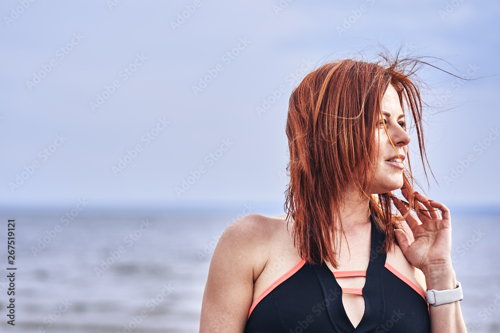 Portrait of a middle-aged woman with red hair walking along the river bank. Sunny spring morning. Close-up.