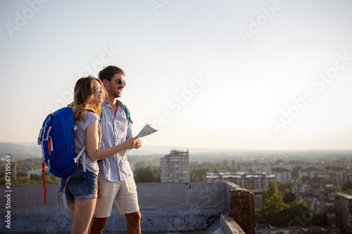 Multiethnic traveler couple using map together on sunny day