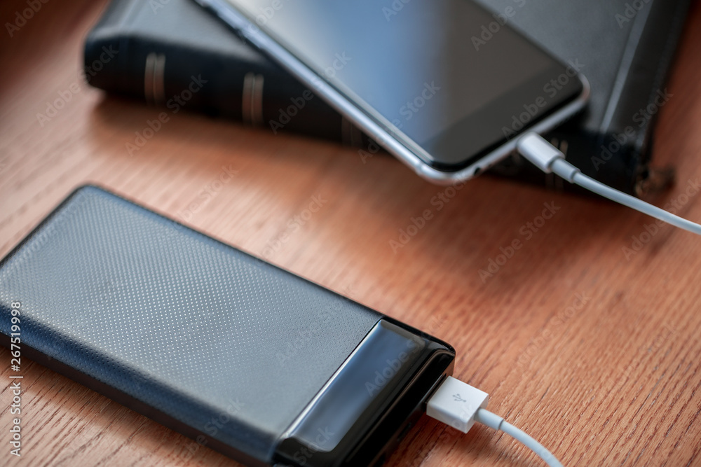powerbank charges smartphone isolated on wood background powerbank charges smartphone isolated on wood background