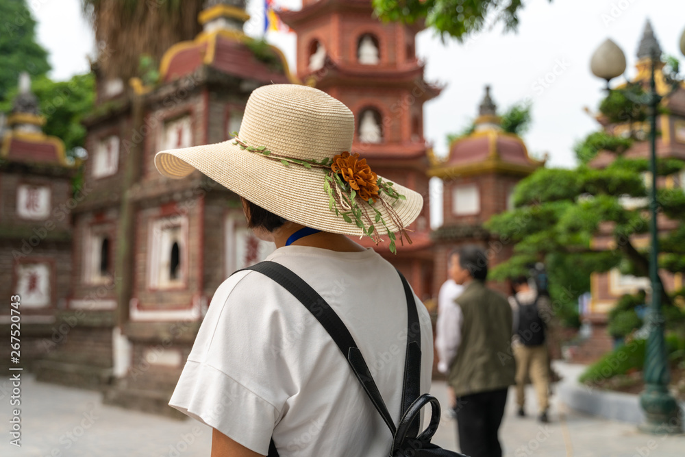 Close-up female tourist visiting Tran Quoc ancient pagoda, the oldest Buddhist temple in Hanoi, Vietnam
