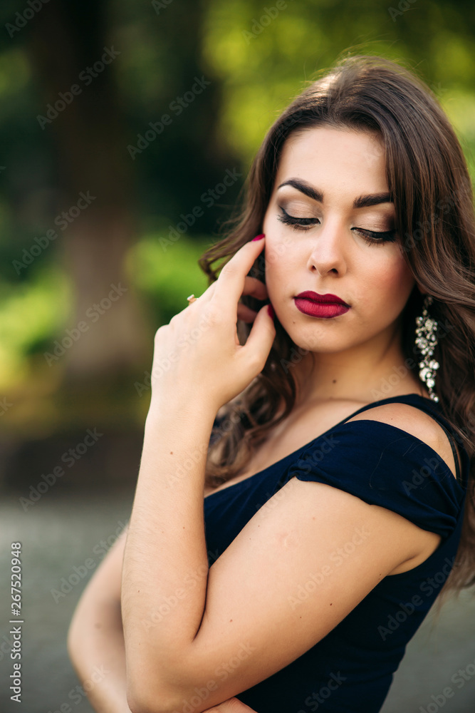 Naklejka premium Close up portrait of woman with evening makeup. Woman close her eyes and show fahion slyle. Backgrounf of blue and green bokeh