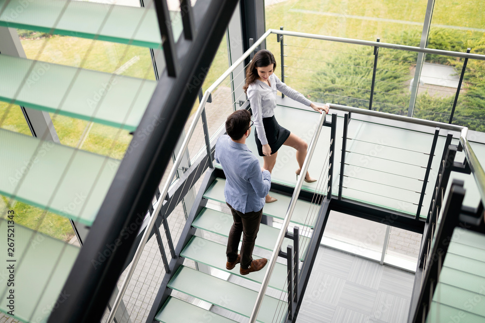 Modern business people walking on stairs in glass hall in office building Modern business people walking on stairs in glass hall in office building