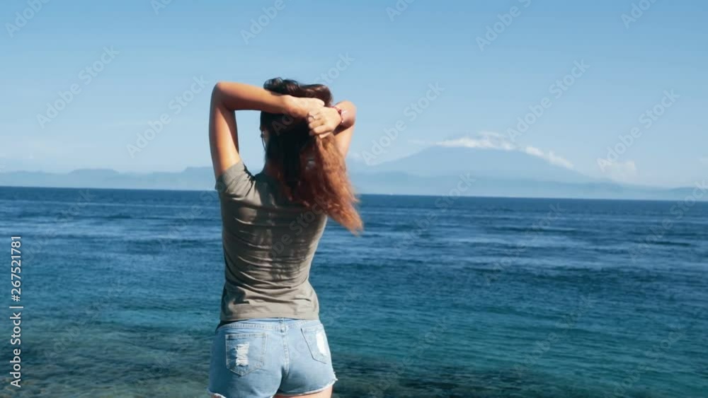 Traveler enjoys view of ocean, mountains. Girl hair flutters in wind, slow motion Traveler enjoys view of ocean, mountains. Girl hair flutters in wind, slow motion