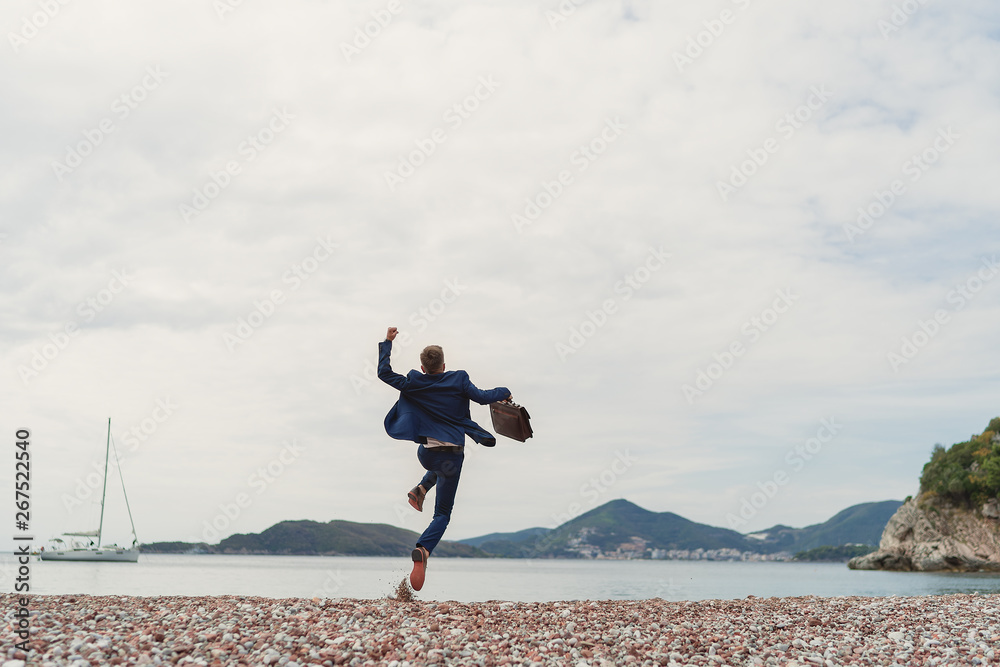 Businessman jumping into the sea holding in hand briefcase. Back view Businessman jumping into the sea holding in hand briefcase. Back view