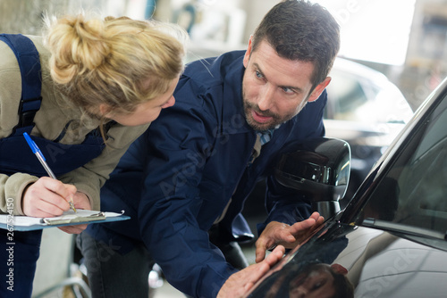woman and man mechanic checking a car