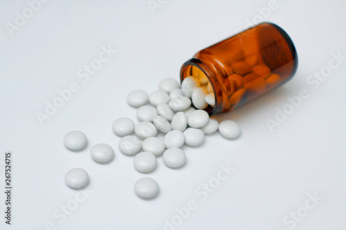 White round pills from yellow glass bottle. On white background. 