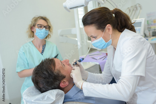 patient at a dentist office with doctor and assistant