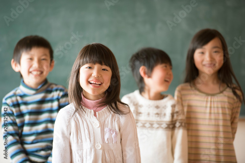 Tapety artystyczne 黒板の前で微笑む小学生